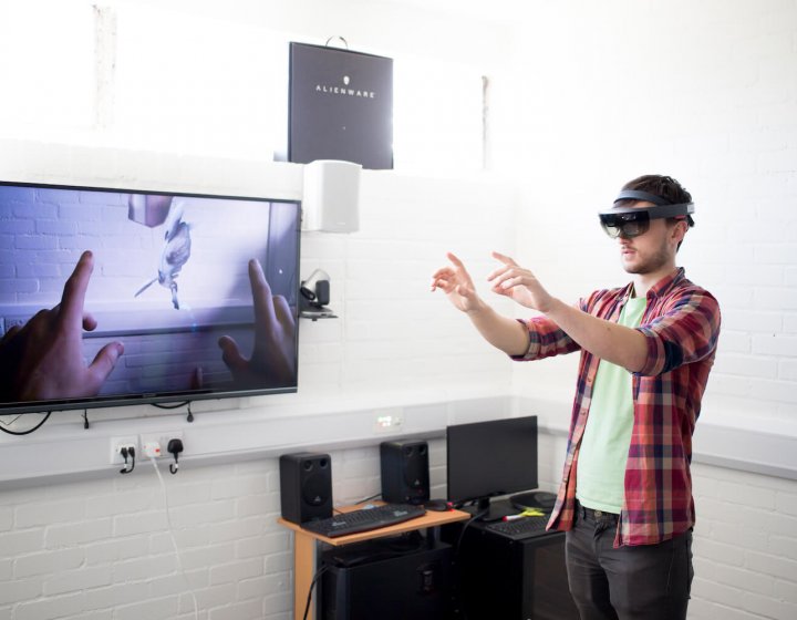 A Falmouth University student wearing a VR headset with a flat screen TV