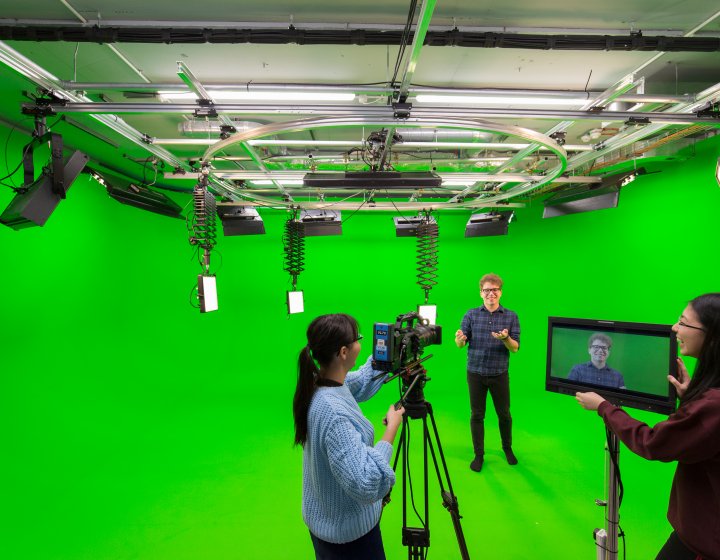 Students shooting a studio with a green screen backdrop.