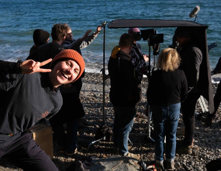 A student poses in front a camera crew on set 