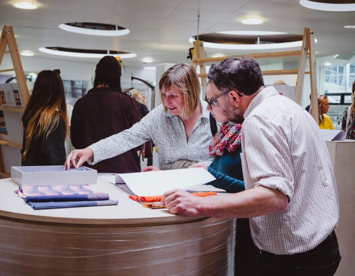 A girl with her parents looking through sketchbooks at a Falmouth University Open Day