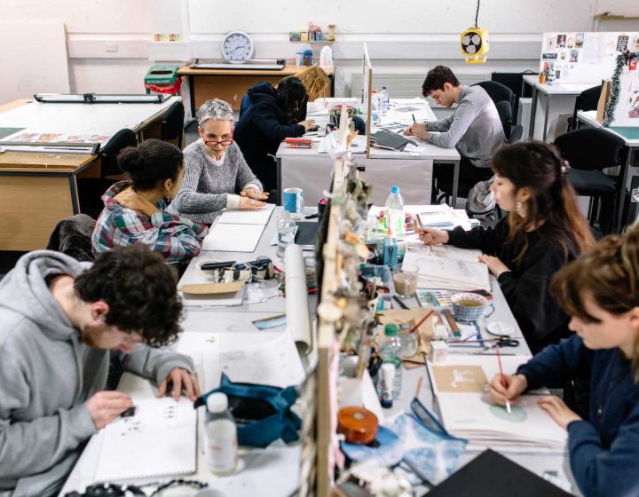 Illustration students in busy studio at desks drawing.