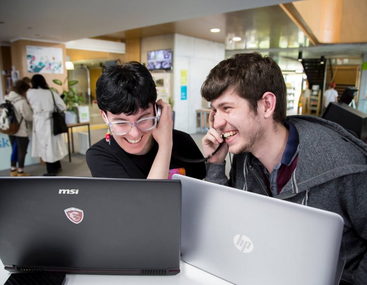 Falmouth University students listening and laughing on their headphones