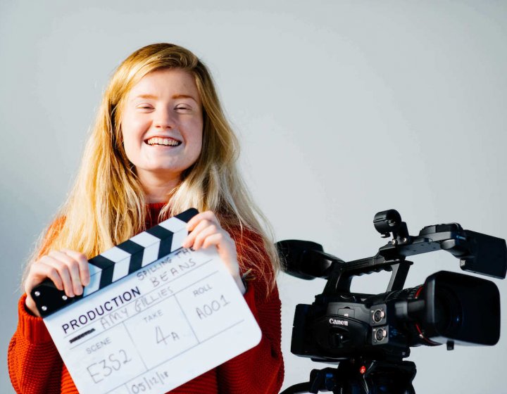 Student holding clapper board next to camera