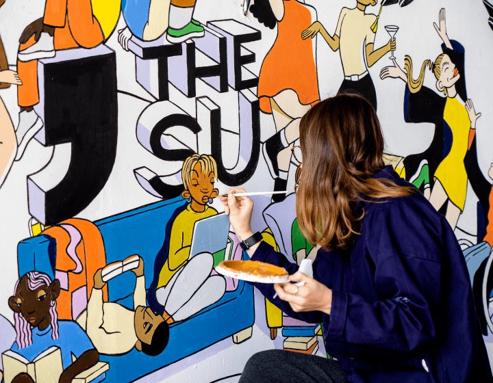 Student painting Students' Union mrual on Penryn Campus