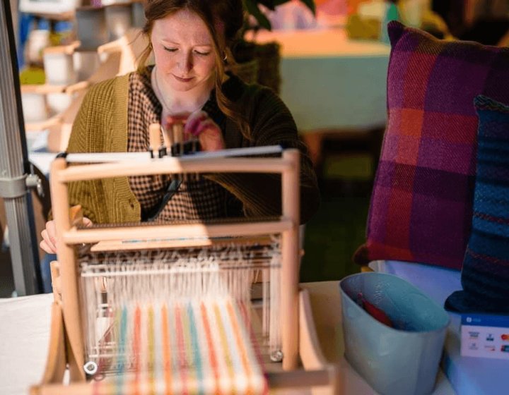 A woman sat in front of a loom