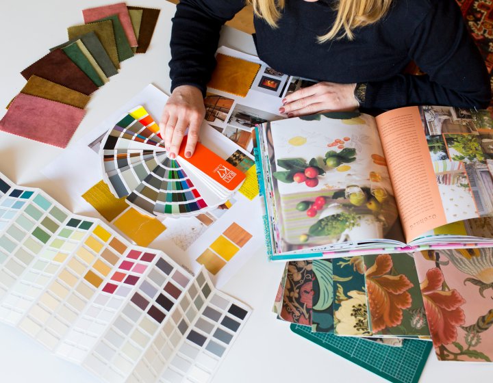A student on interior design sitting at a table with books, paint and fabric samples in front of them
