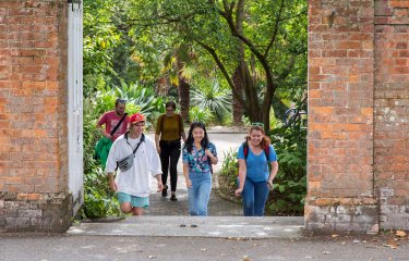 Students walking towards a gateway between red brick walls on Falmouth campus.