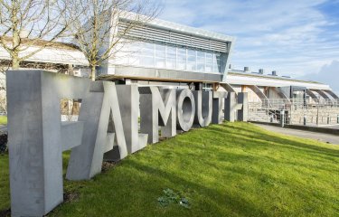 Falmouth University concrete sign in front of glass building