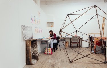 Female student in a studio with large metal sculpture