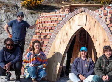 Architecture students outside a brick building with wooden arch