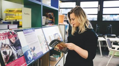 A Falmouth University student looking through a Postgraduate study guide
