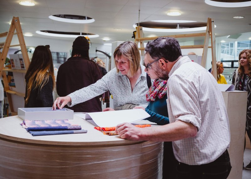 A girl with her parents looking through sketchbooks at a Falmouth University Open Day