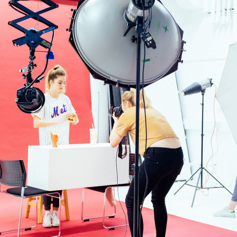 Students shooting in a studio set up with pink backdrop.