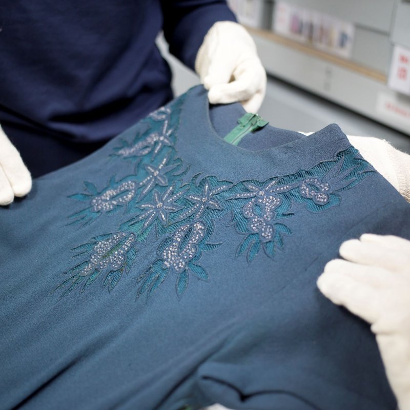 Close crop of two people wearing white gloves examining a garment in the Textiles & Dress Collection