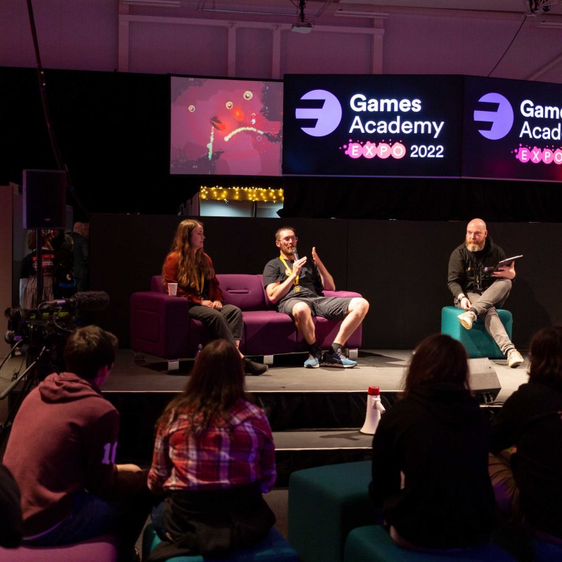 Speakers sit on sofas, delivering talks at the 2022 Games Expo